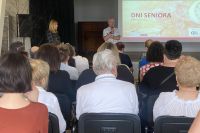 Na zdjęciu seniorzy siedzący na krzesłach w sali podczas prezentacji Dni Seniora  