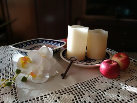 na zdjęciu dwie świeczki na talerzu, jabłka i klucz 