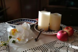na zdjęciu dwie świeczki na talerzu, jabłka i klucz 