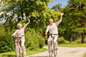dwójka seniorów - kobieta i mężczyzna na leśnej ścieżce jadą na rowerach